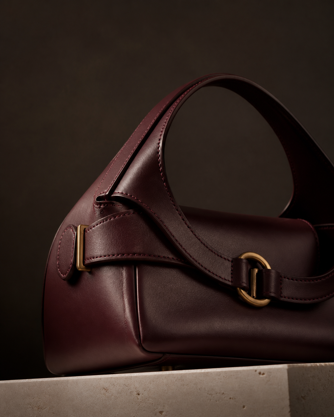 Oxblood leather handbag detail showing precise stitching and brass hardware